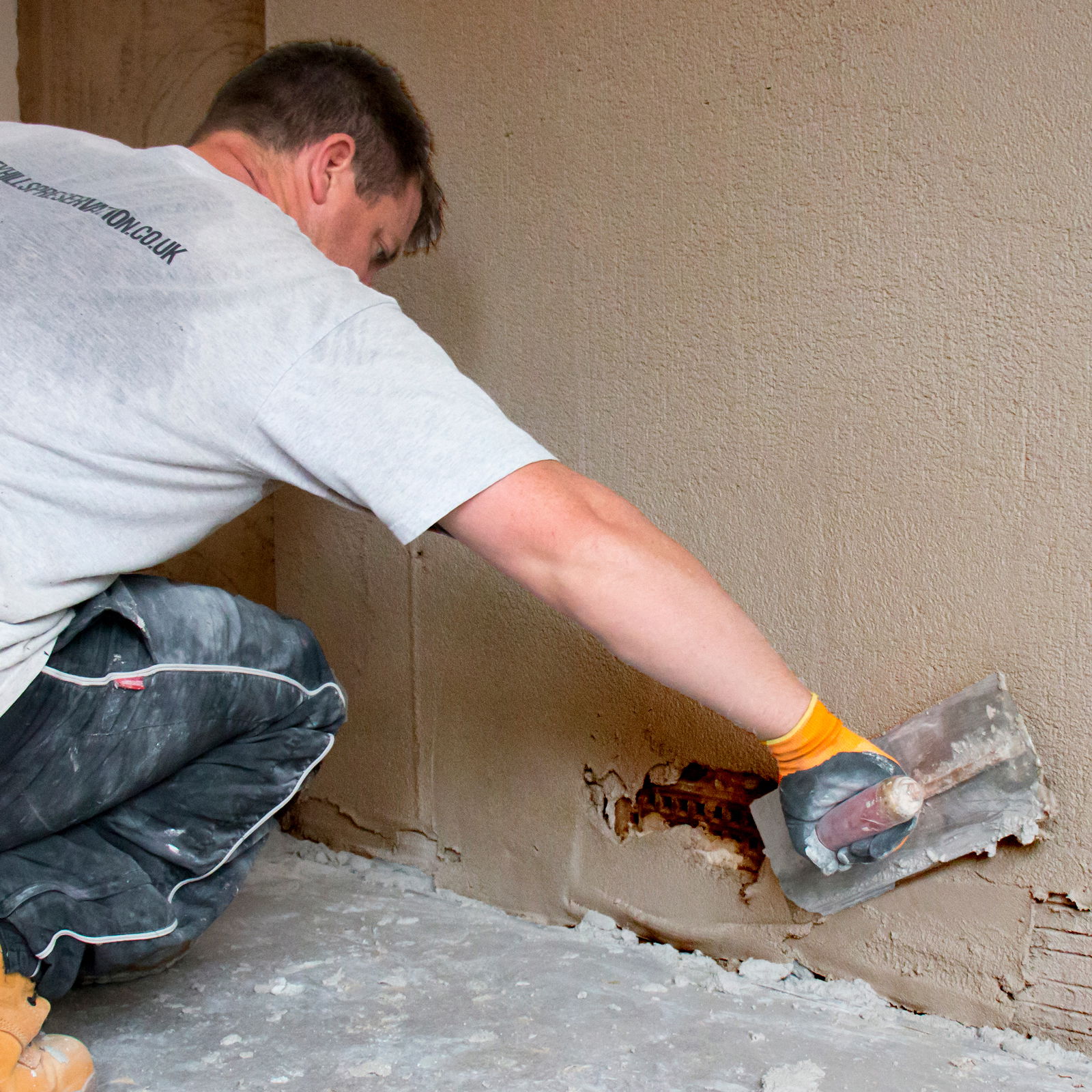 A worker applying a plaster coat on a wall with a trowel.