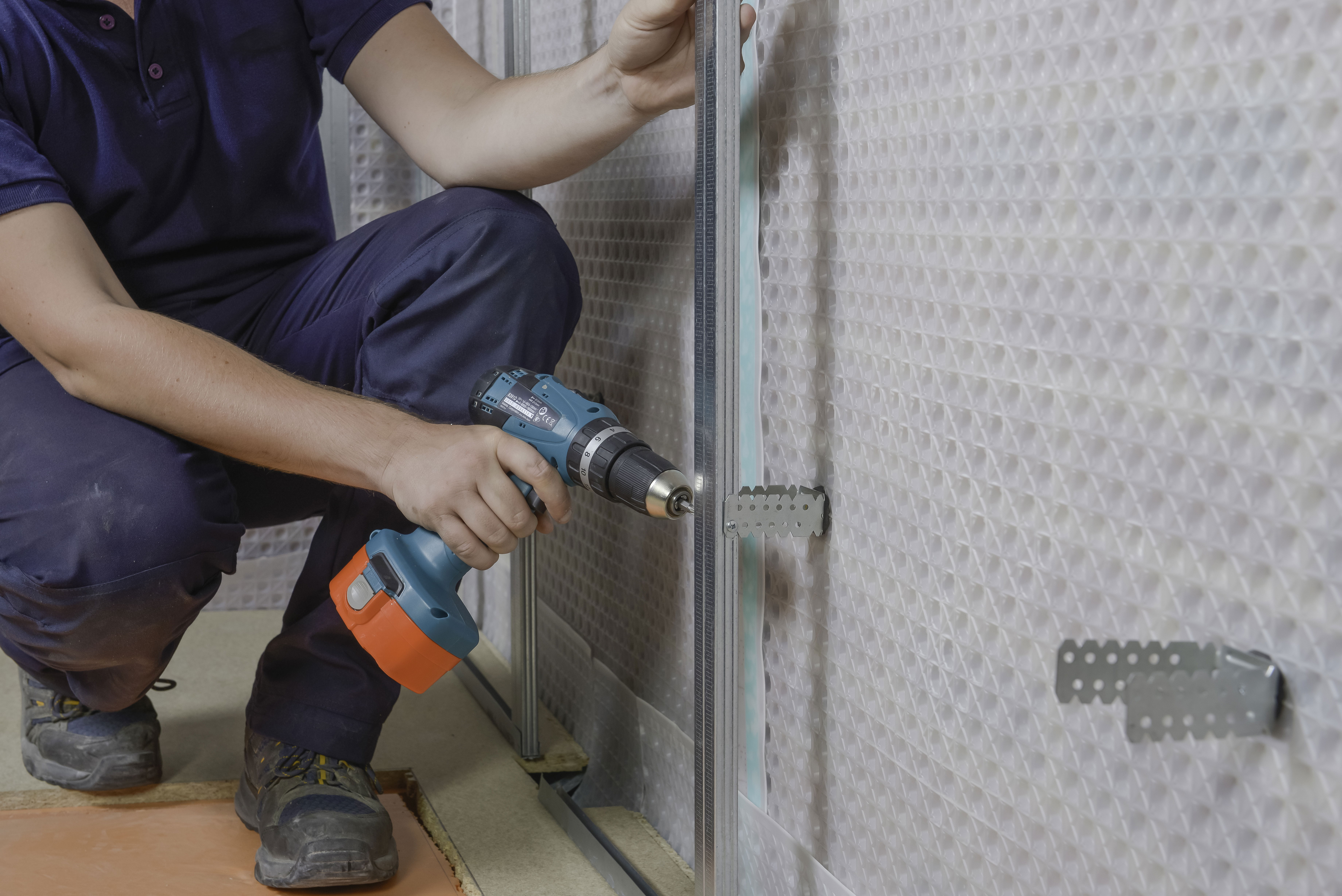 A contractor measures a cavity drainage membrane in an existing membrane.