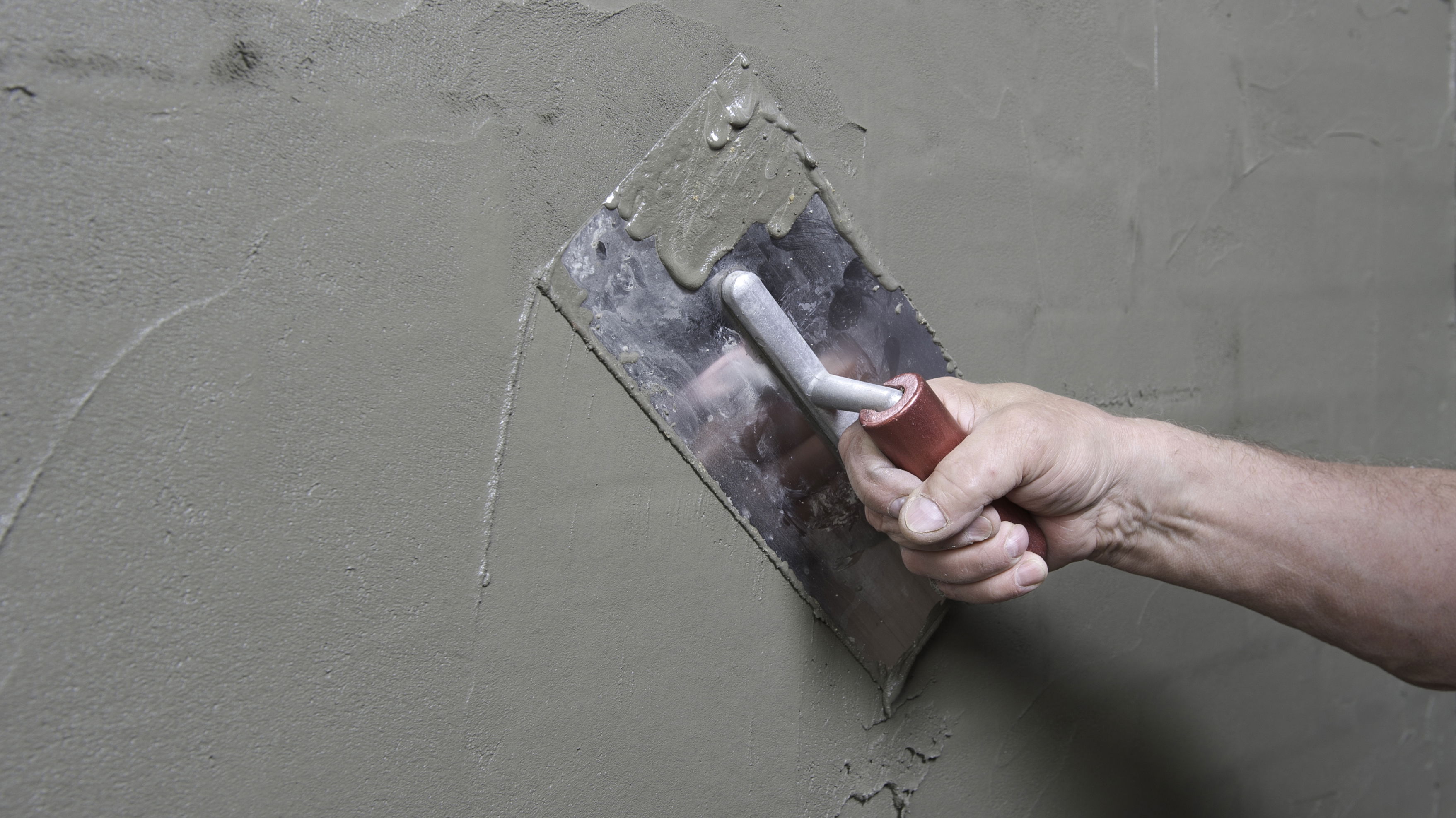 A contractor with a trowel applying a waterproof plaster finish.