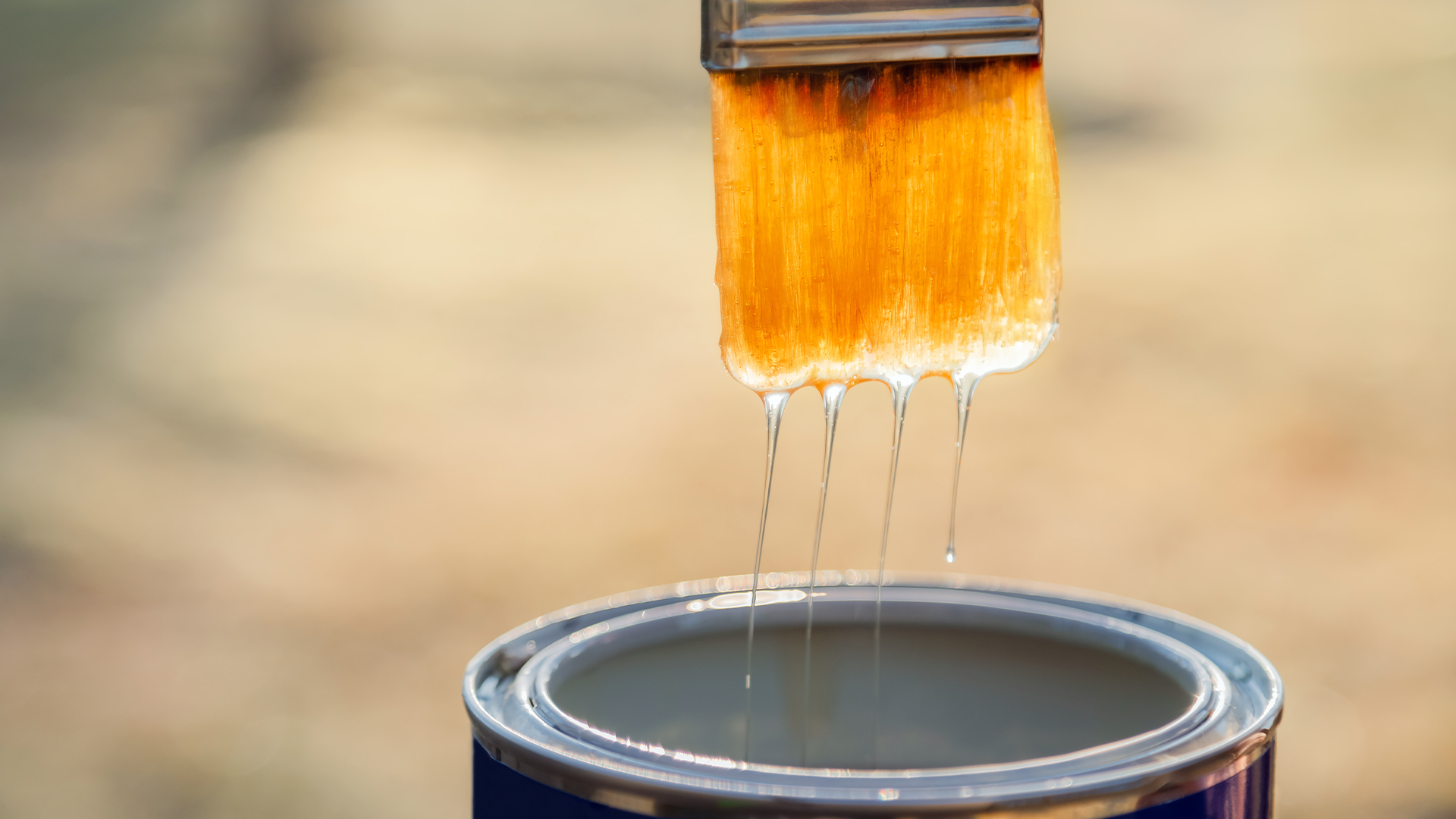 Varnish dripping onto a brush into the can.