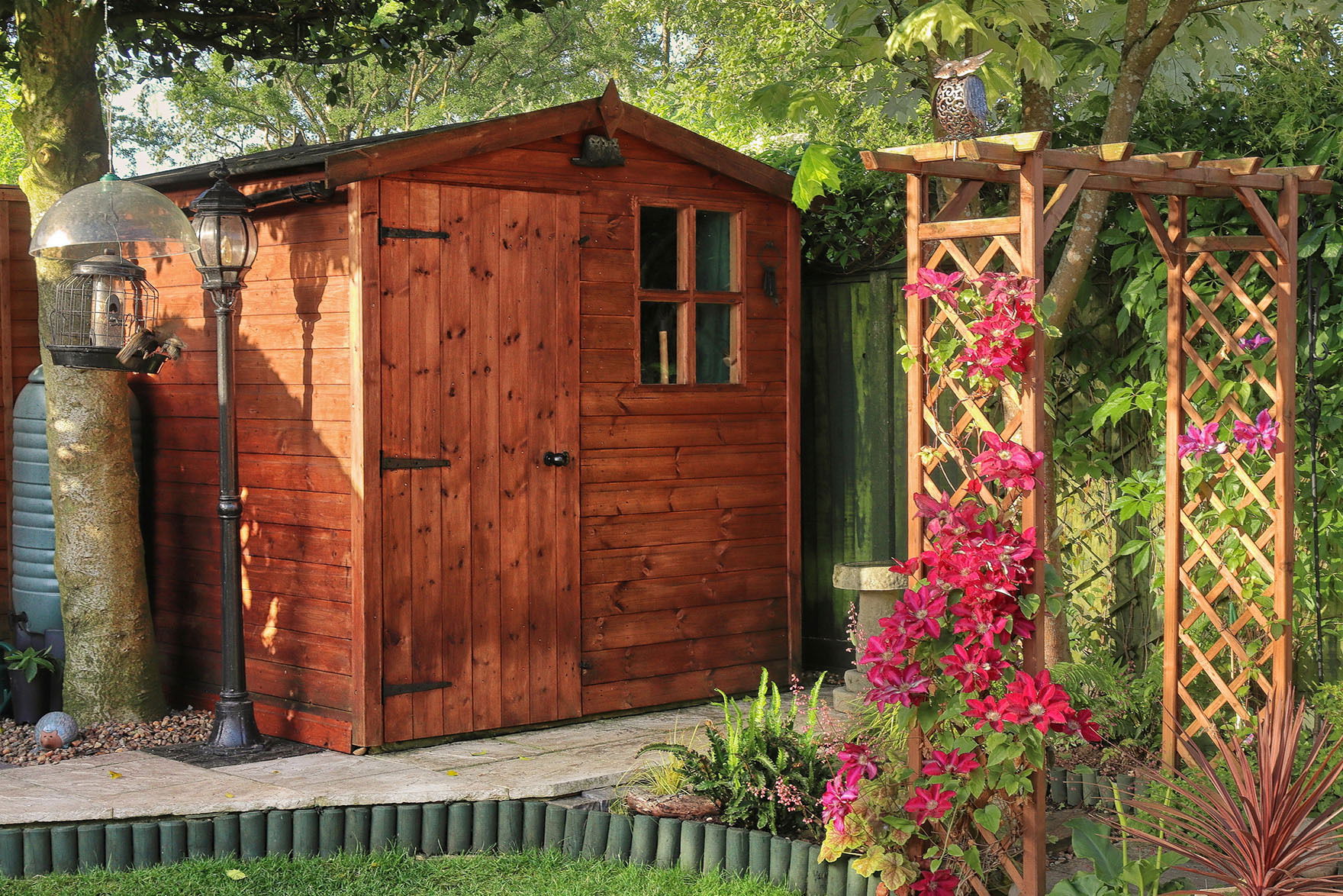 English back garden with shed and arch covered in Clematis.