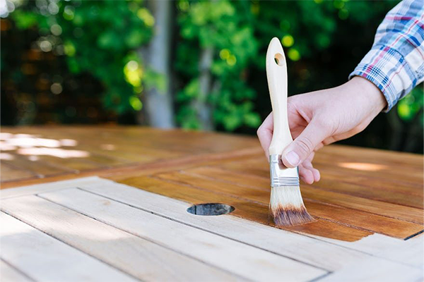 A man applies an oil stain to a wooden table.