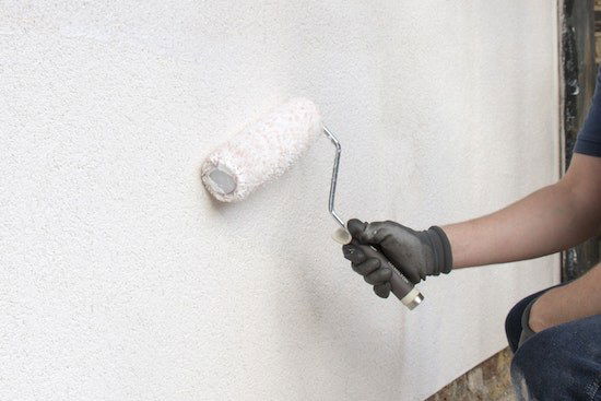 A man painting a wall by roller.
