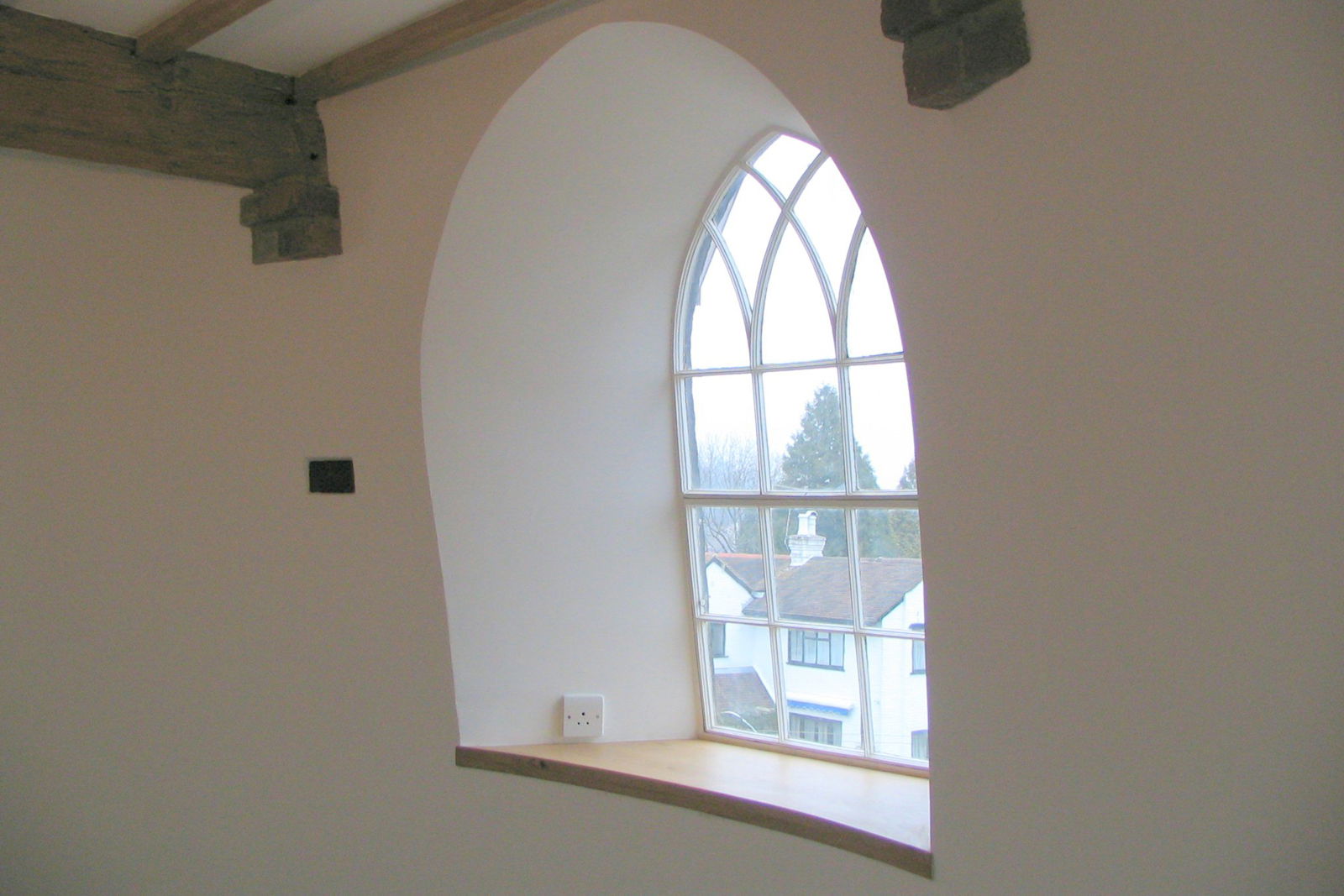 A rounded window with a view on houses.