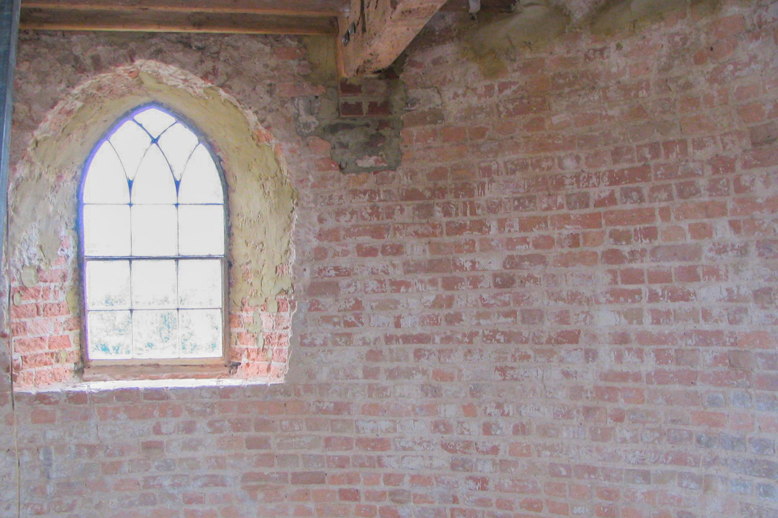 The inside wall of a windmill with a single window.