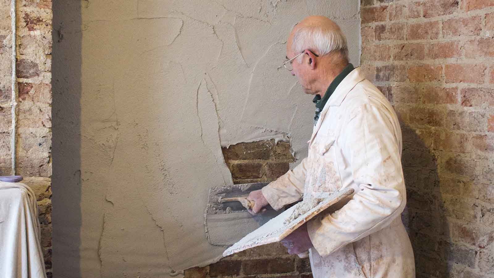A contractor applying a waterproof plaster on a wall.