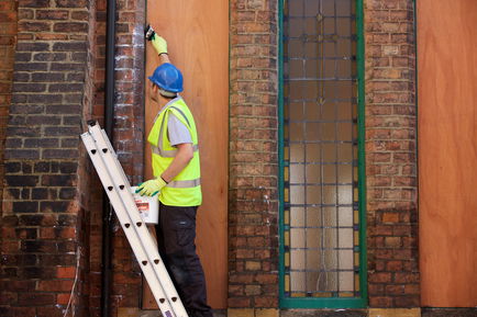 A contractor applying Stormdry Masonry Protection Cream on a church window.