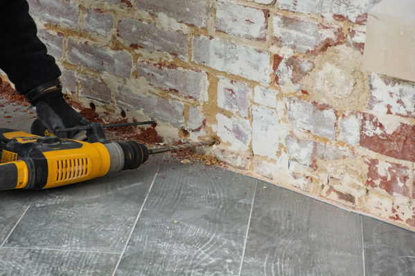 Drilling a remedial damp-proof course prior to Dryzone DPC Cream installation.