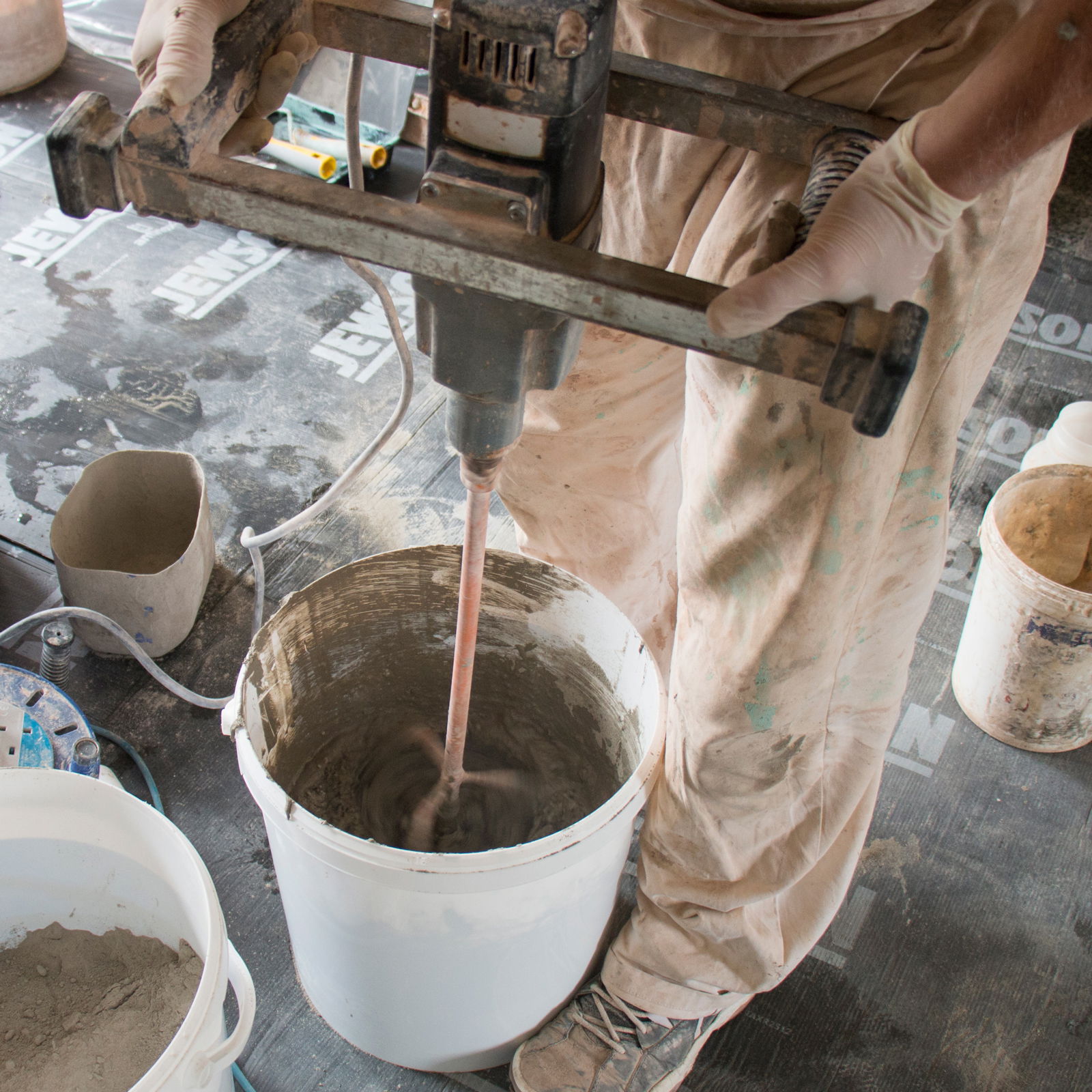 A worker mixing a render with a paddle mixer.