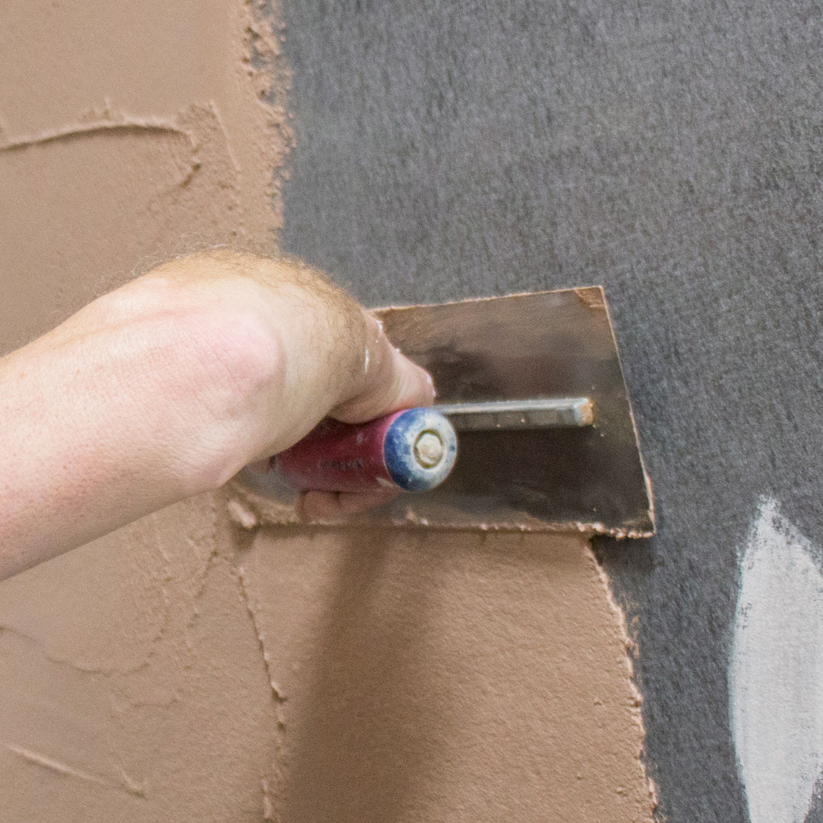 Someone applying a skim coat with a trowel.