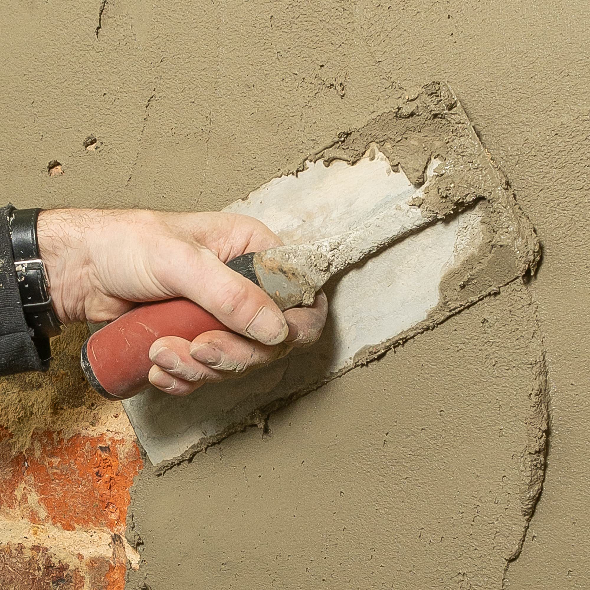 A contractor applies Dryzone Damp-Resistant Plaster with a trowel.