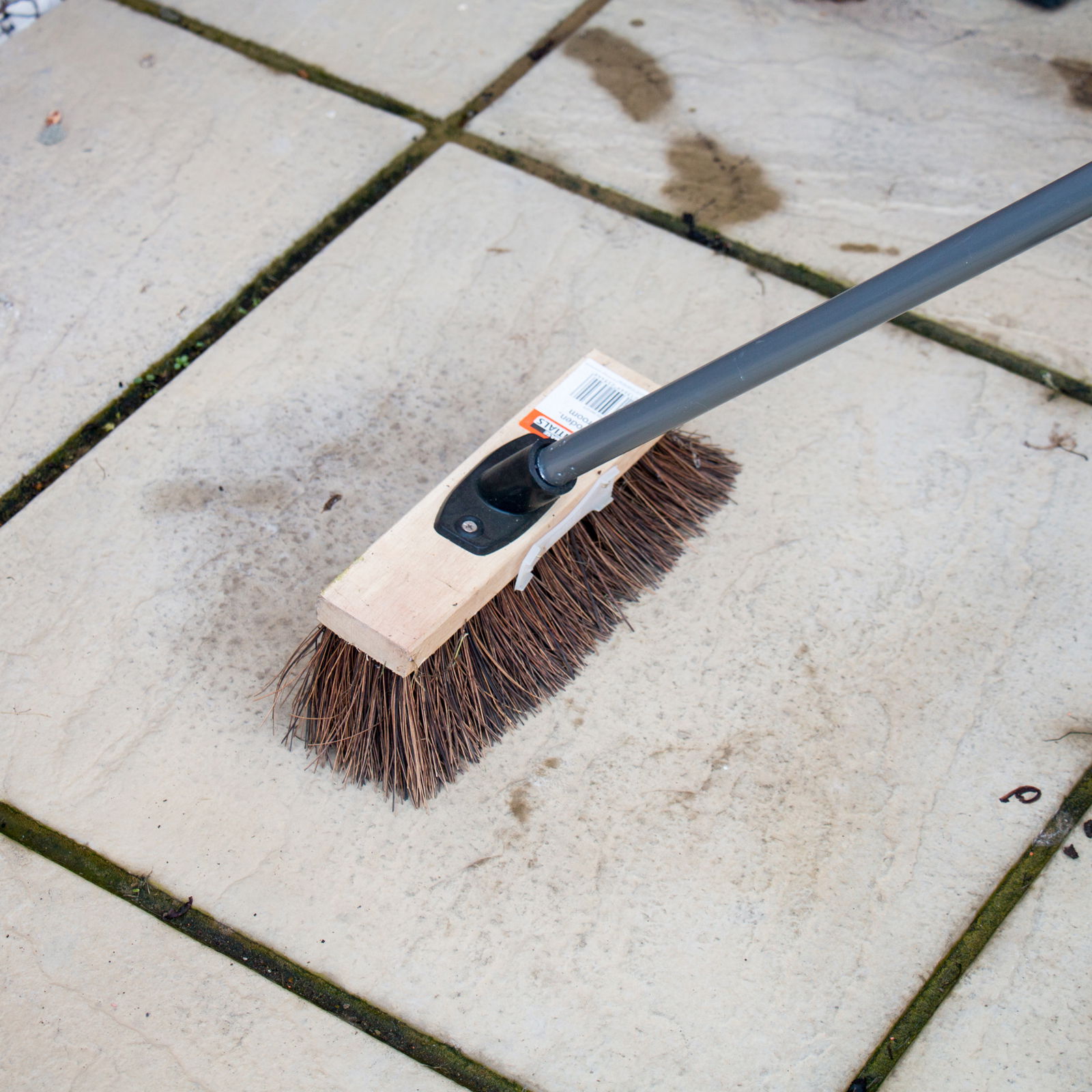 Using a broom to remove debris from a patio in preparation for Roxil Patio Cream