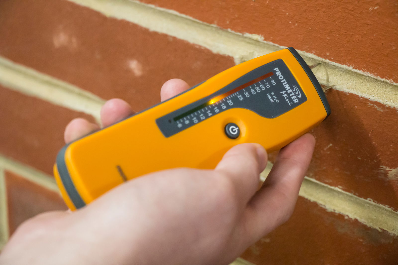 A protimeter moisture meter in use on a masonry wall.
